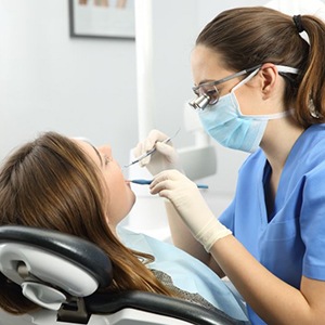 a dentist carefully checking a patient’s mouth