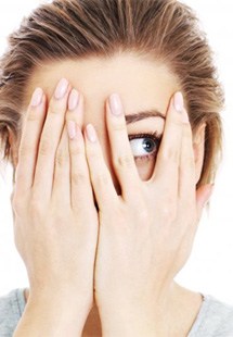 a woman covering her face and peeking through her fingers