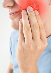 a person holding their cheek due to tooth pain