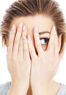 a woman covering her face and peeking through her fingers