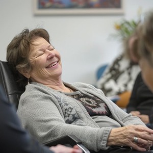 an older woman with multiple sclerosis smiling among friends