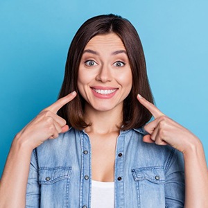 a woman smiling and pointing at her teeth